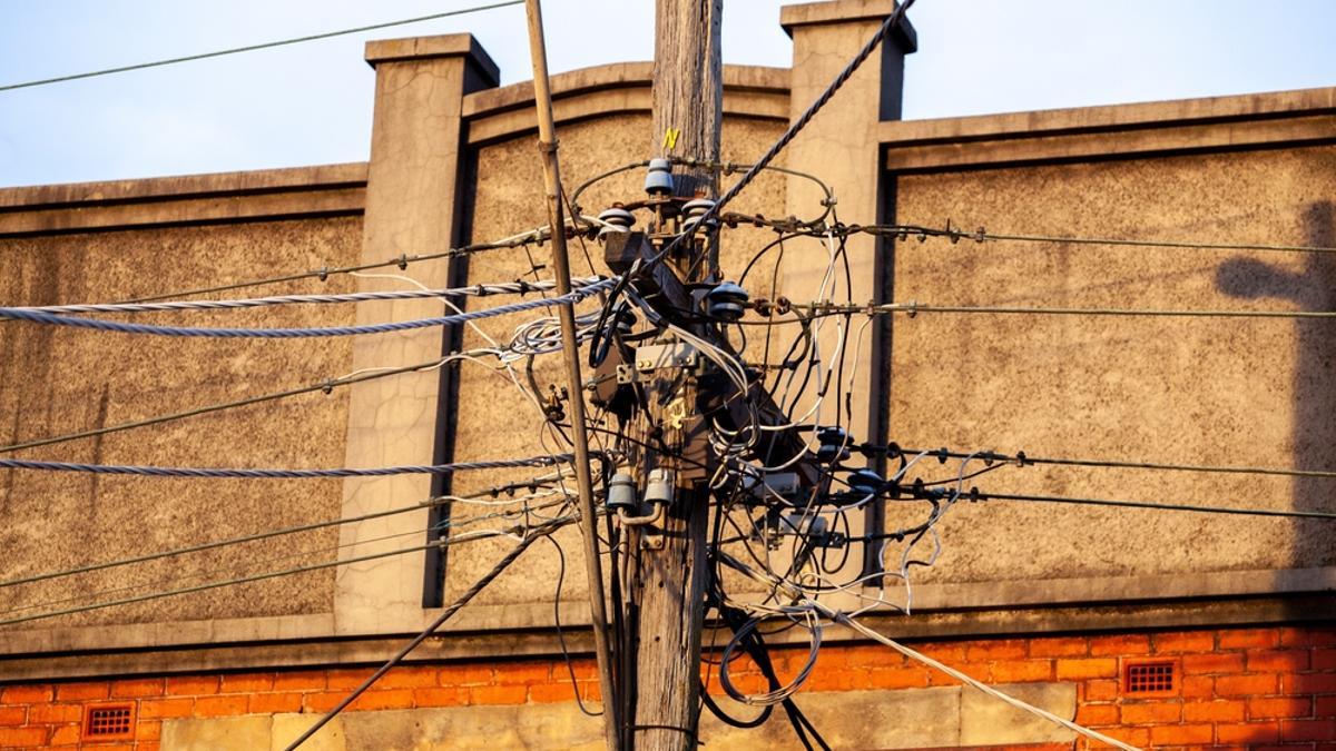 Cables en un poste junto a una fachada.