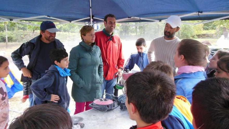 Arriba, Vitor Reis explica su obra a escolares, junto a Nando Álvarez y la concejala Cristina Martínez. A la izquierda, en plena tarea.