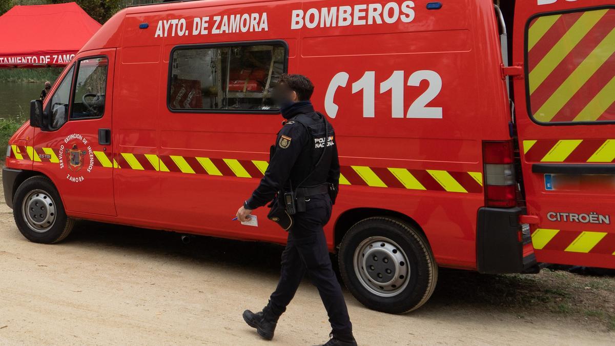 Un agente de la Policía Nacional camina por delante de la furgoneta de los bomberos de Zamora.