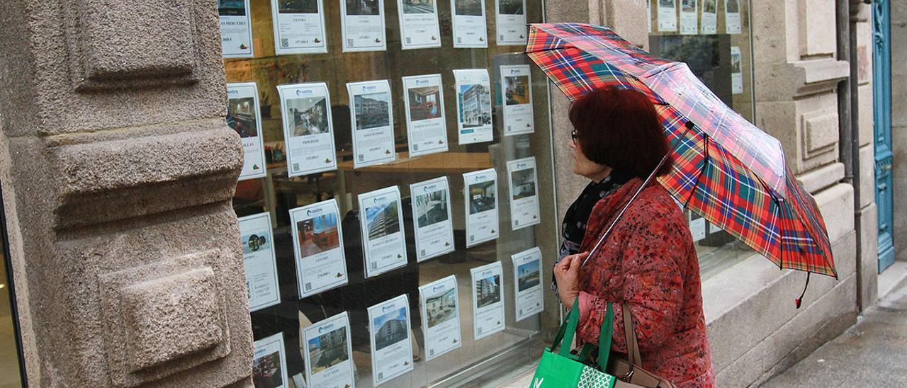 Una mujer consulta los anuncios en el escaparate de una inmobiliaria en Ourense