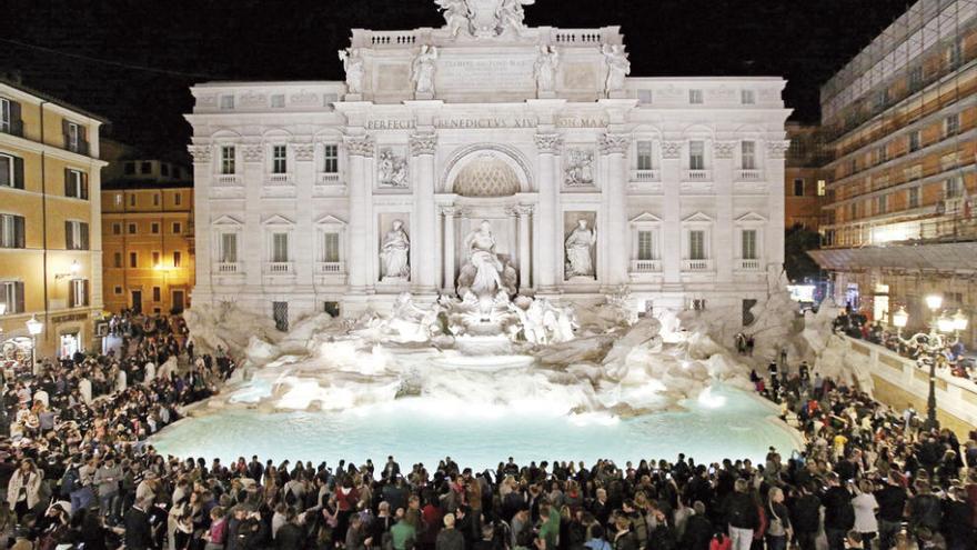 Personas observan la Fontana de Trevi iluminada, accesible al público desde ayer y tras los trabajos de restauración. // Efe