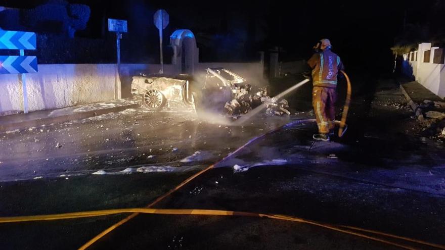 Un bombero apaga los restos del vehículo.