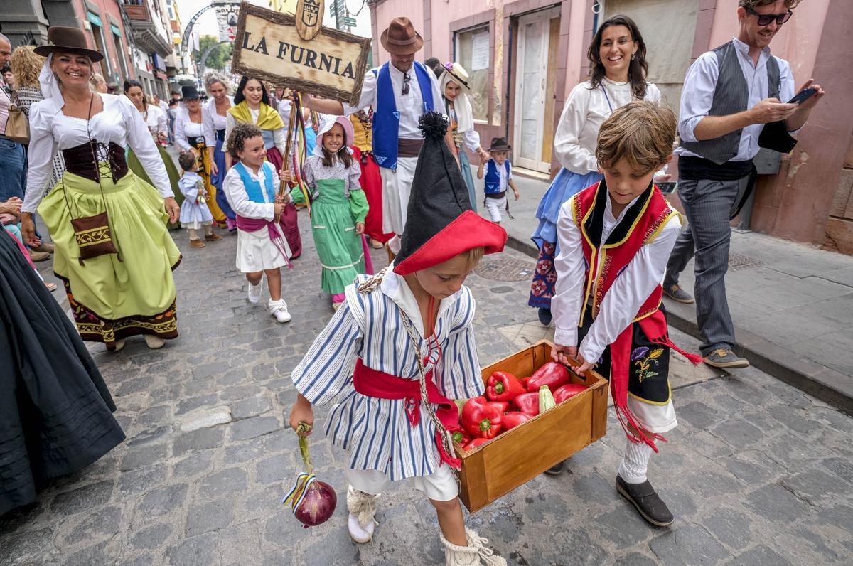 Dos niños cargan la ofrenda durante el inicio de la romería
