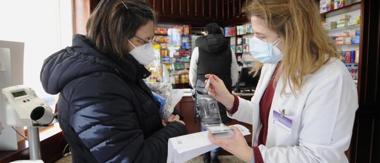 Una clienta realizando una compra, con mascarilla, en la Farmacia Eirín de A Estrada.   | // BERNABÉ / JAVIER LALÍN