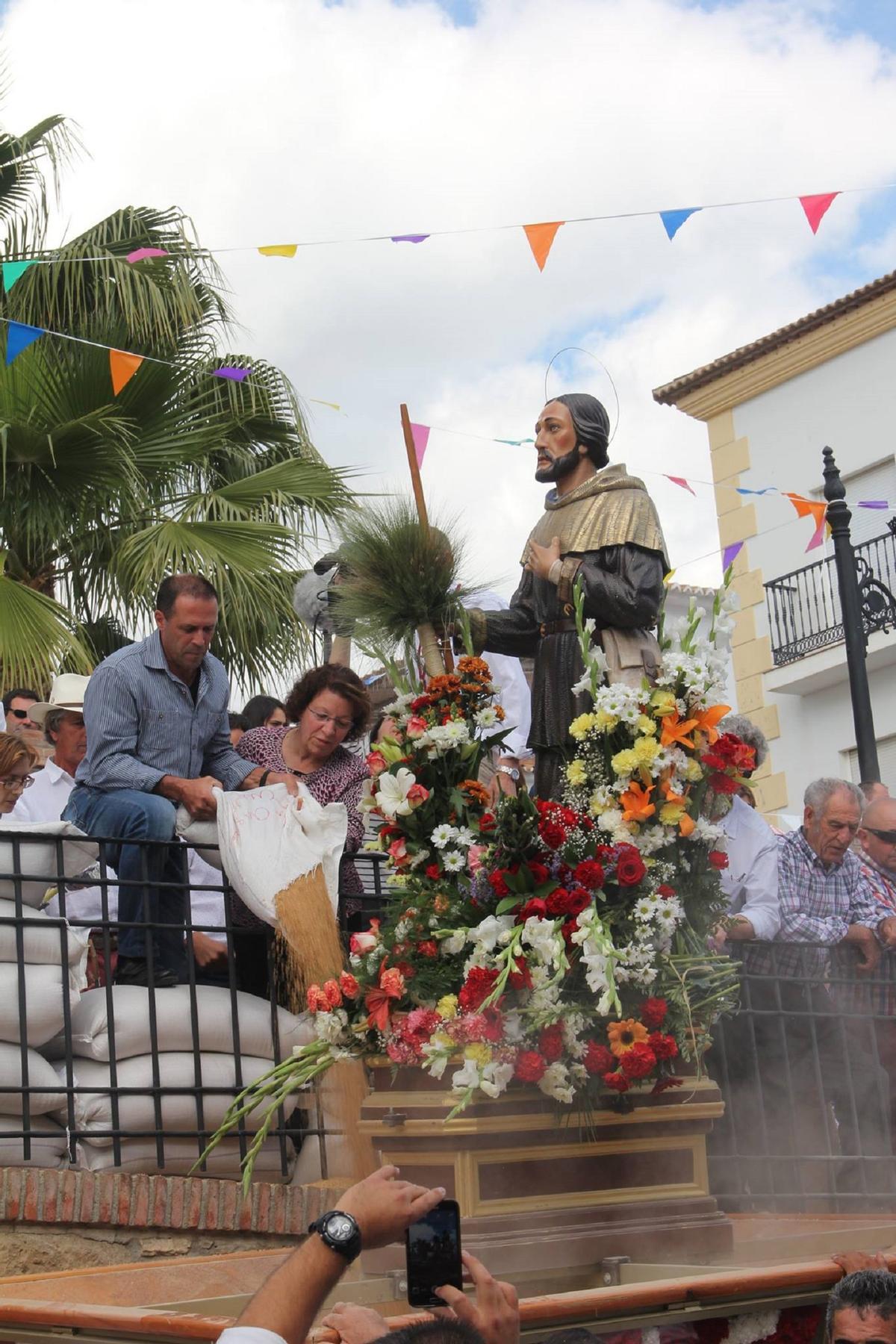 Los vecinos de Periana lanzan trigo al paso de San Isidro.