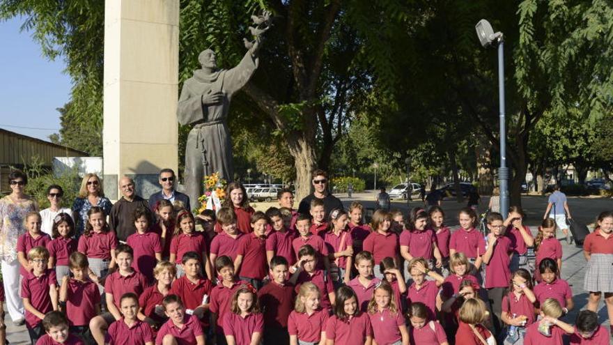 Foto de familia de los estudiantes y sus profesores junto a la estatua del santo.