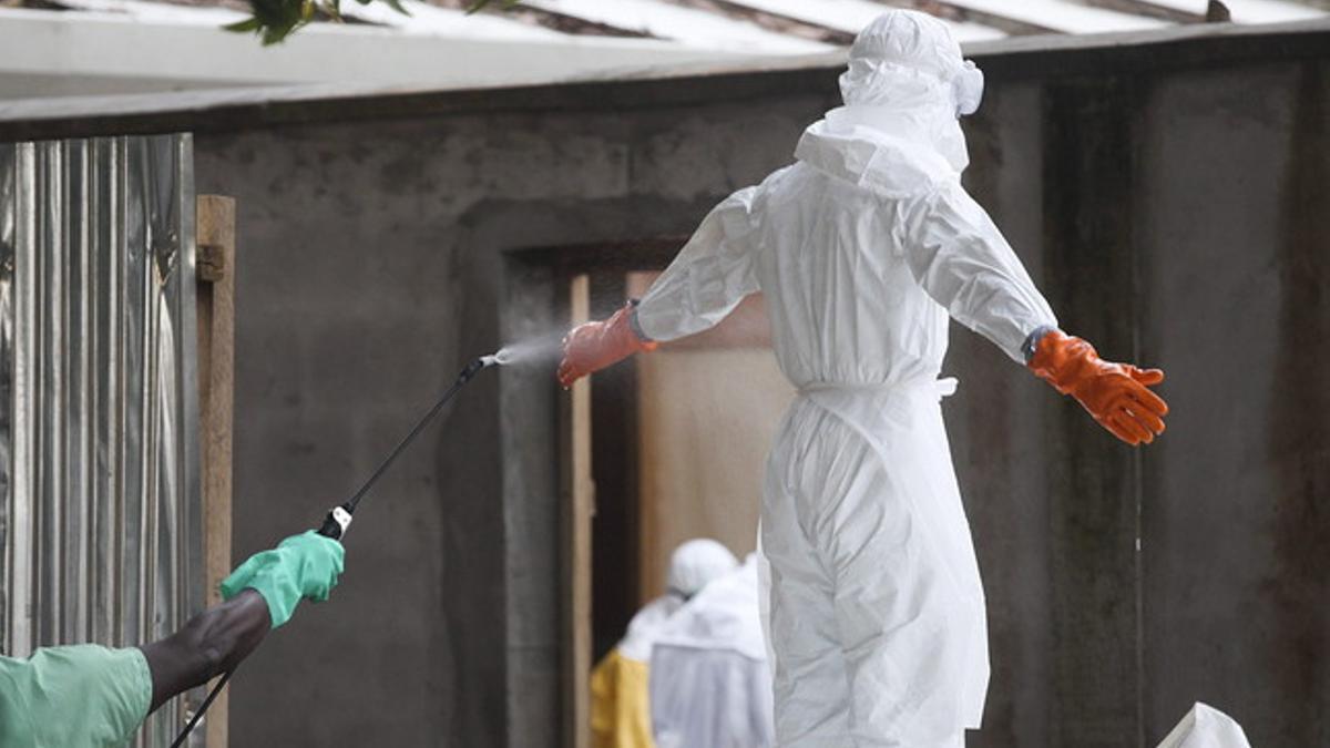 Una enfermera es rociada con desinfectante en un centro sanitario de Liberia.
