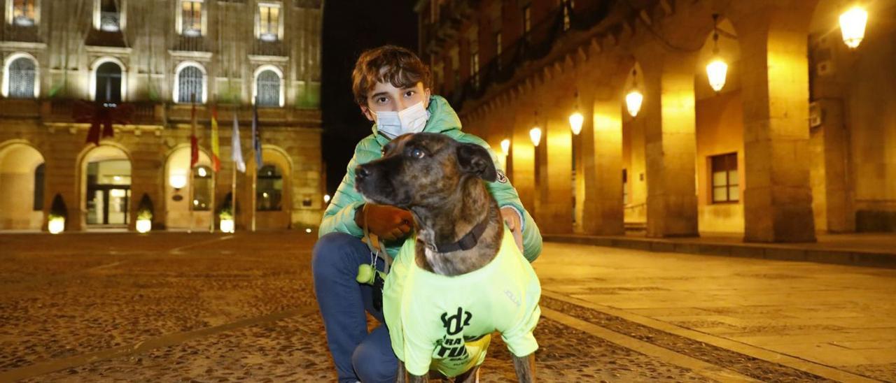 Ricardo Tucho, con su perro “Beto”, ayer, delante del Ayuntamiento, con luces verdes en la fachada en apoyo de la lucha contra la enfermedad de Perthes. | Marcos León