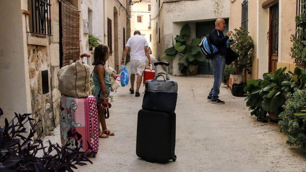 Una niña, con las maletas, espera a sus padres para marchar.