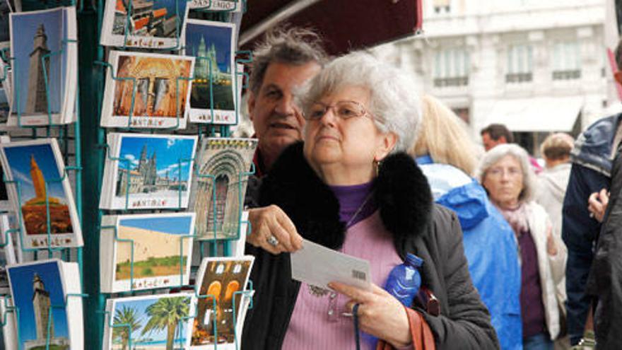 Turistas observan postales en A Coruña.