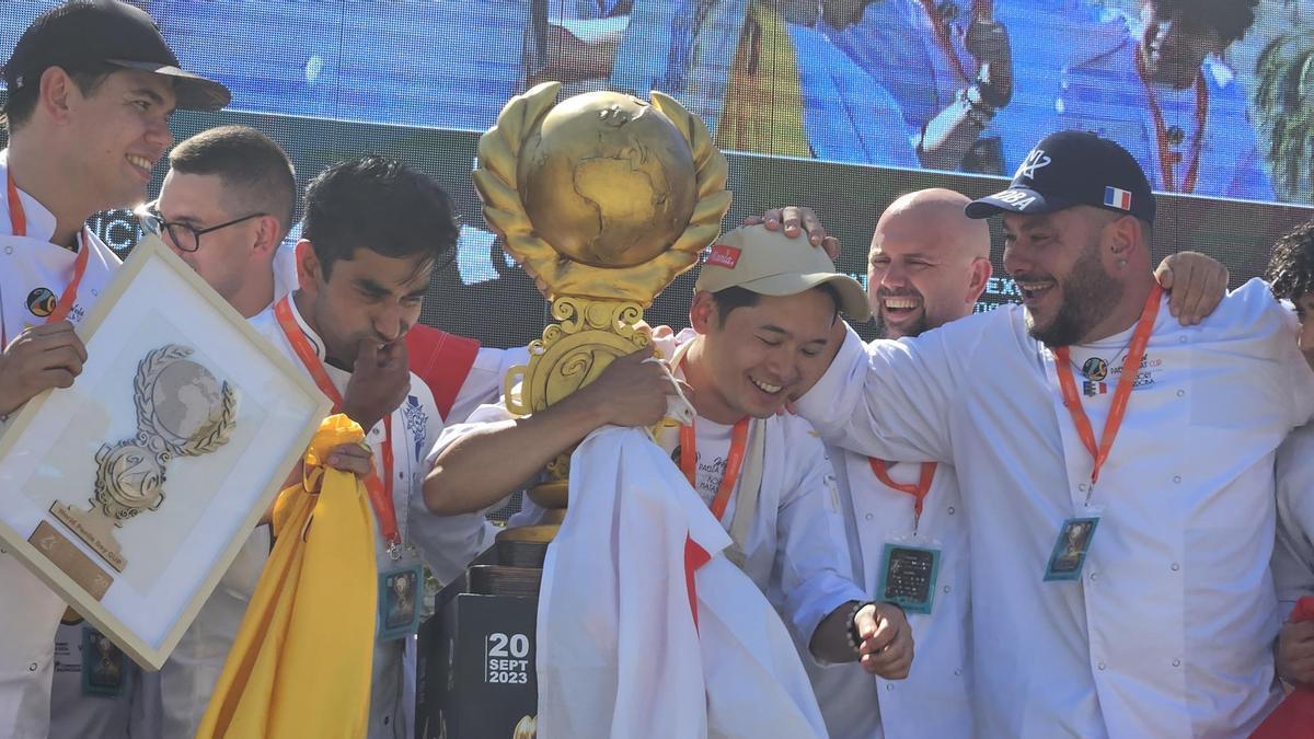 El chef japonés celebra la victoria con el trofeo rodeado de sus colegas