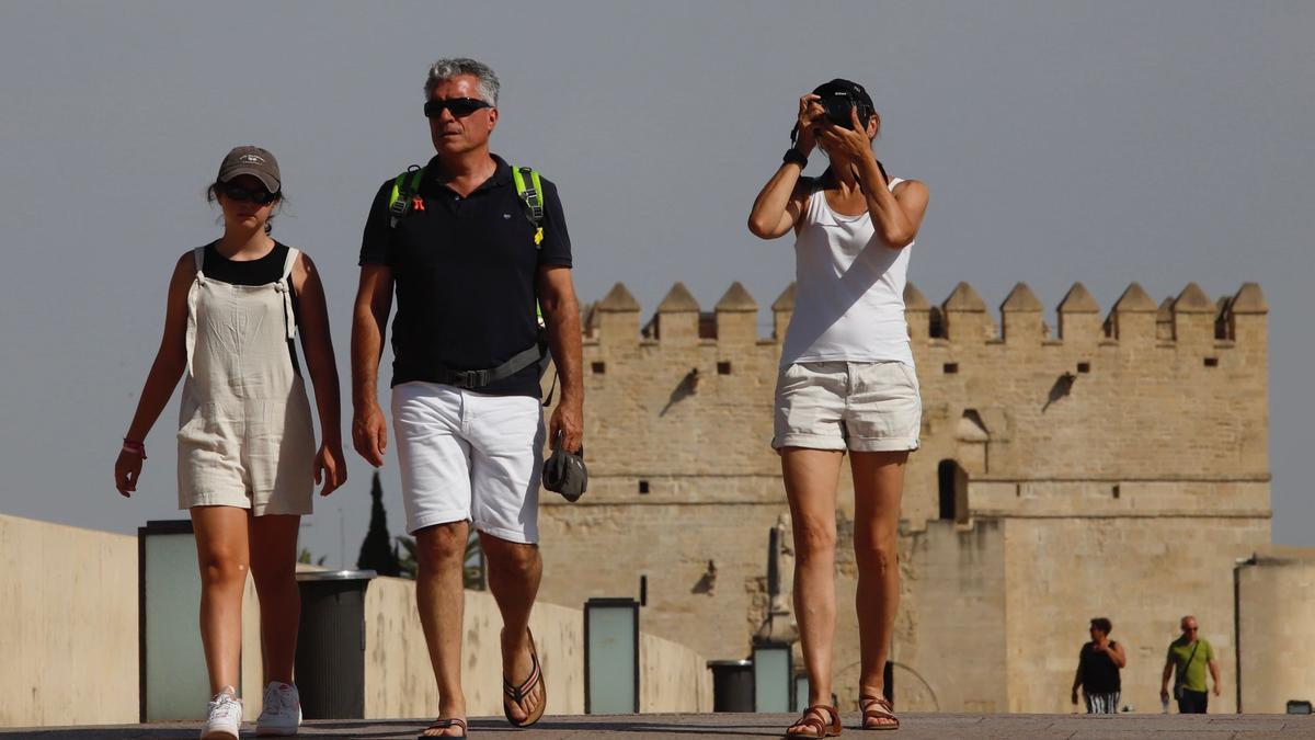 Tres turistas cruzan el Puente Romano en plena ola de calor.