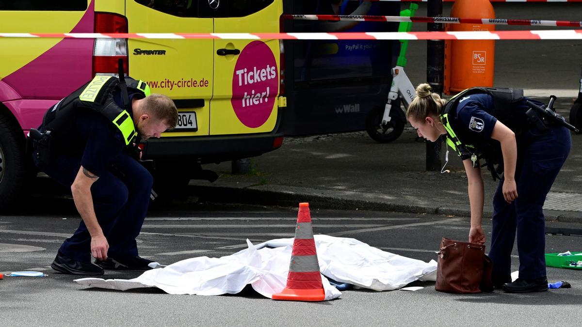 Los agentes de policía cubren el cuerpo de la persona muerta, en un área acordonada