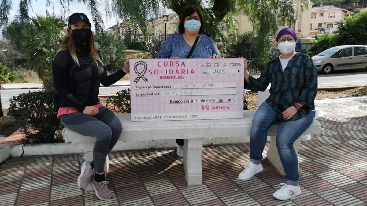 María Ferrer y las organizadoras e la Cursa Solidària muestran el cheque entregado a la Fe
