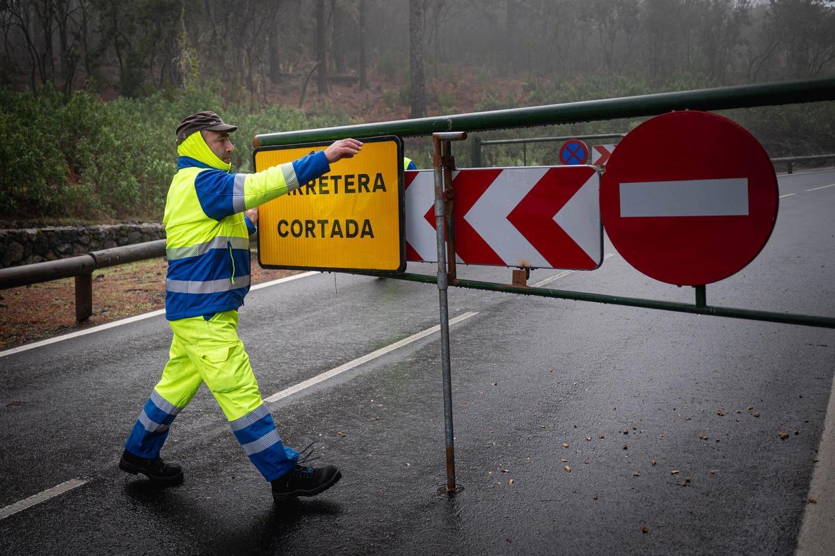 Un operario retira el cartel de carretera cortada tras una nevada en el acceso al Parque Nacional del Teide