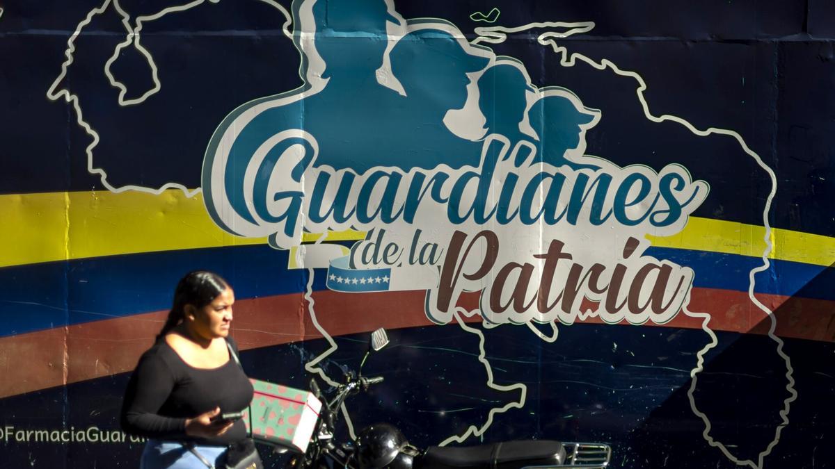 Una persona camina frente a un mural en una zona comercial en Caracas, Venezuela.