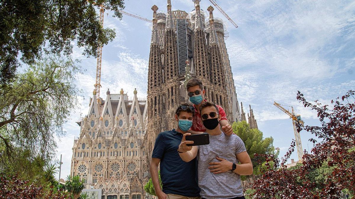 Tres jóvenes con mascarilla se hacen un selfi ante la Sagrada Família, el pasado 10 de julio