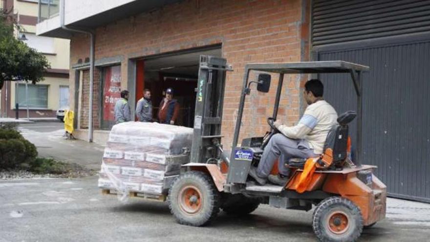 Trabajadores realizan trabajos en la zona exterior del bajo comercial, en As Barxas.  // Carmen Giménez