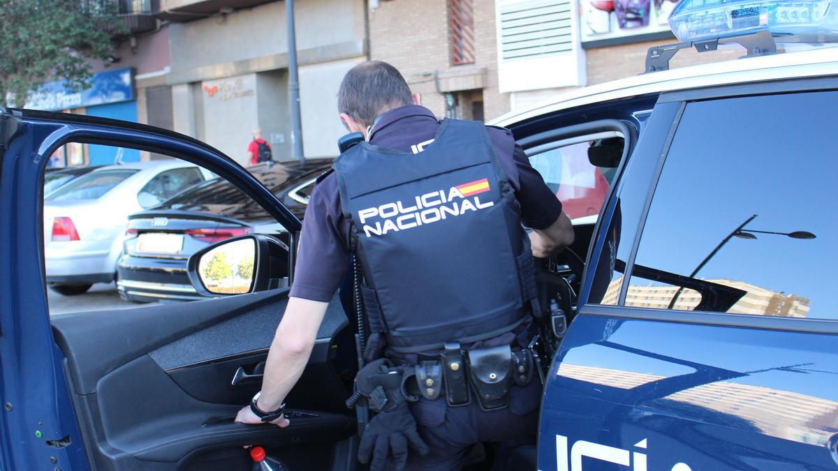 Un agente de la Policía Nacional, entrando en un coche patrulla.