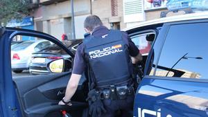 Archivo - Un agente de la Policía Nacional, entrando en un coche patrulla.
