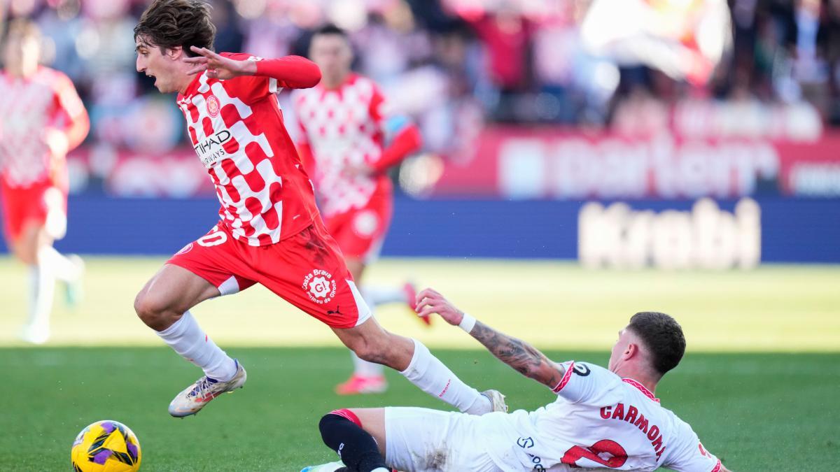GIRONA, 18/01/2025.- El futbolista del Girona FC Bryan Gil Salvatierra (i) se enfrenta a José Ángel Carmona (d), del Sevilla FC, durante su partido de LaLiga EA Sports en el Estadio de Montilivi de Girona este sábado. EFE/ David Borrat