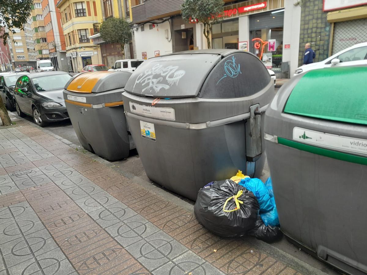 Bolsas de basura junto a un contenedor lleno en Sama tras la avería estos días de varios camiones.