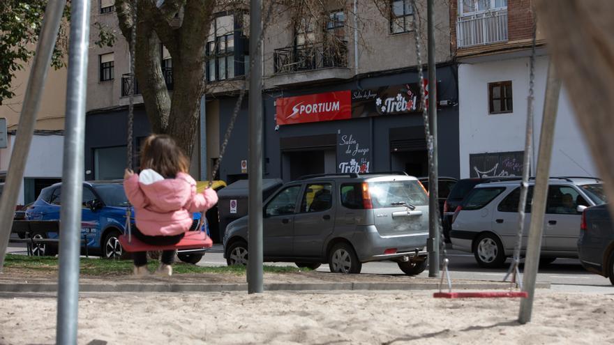 Una niña juega en un columpio junto a un colegio a unos metros de una casa de apuestas en Zamora capital.