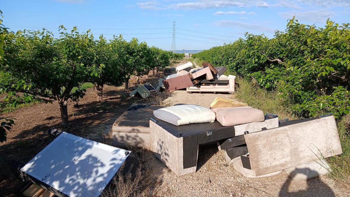 Un vertido de sofás en el camino de acceso a un campo.