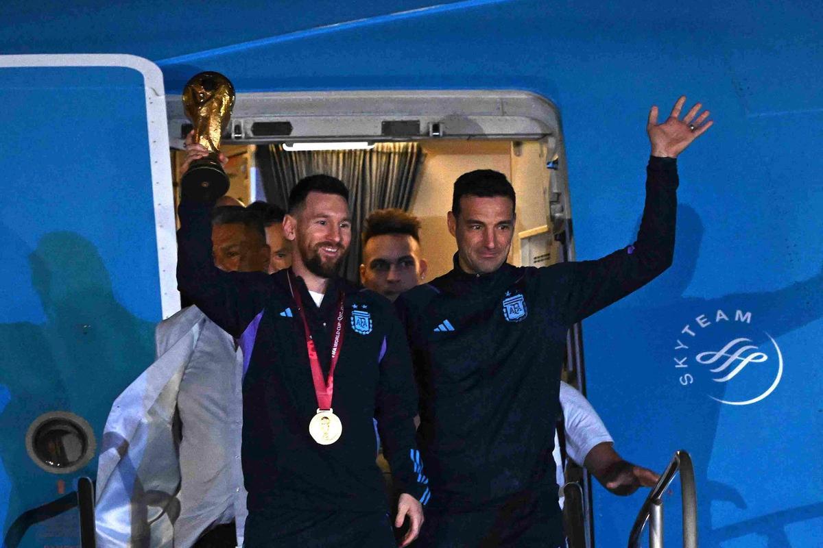 El capitán y delantero de Argentina, Lionel Messi (izq.), sostiene el trofeo de la Copa Mundial de la FIFA junto al seleccionador argentino, Lionel Scaloni, al bajar del avión a su llegada al aeropuerto internacional de Ezeiza. El capitán y delantero de Argentina, Lionel Messi (izq.), sostiene el trofeo de la Copa Mundial de la FIFA junto al seleccionador argentino, Lionel Scaloni, al bajar del avión a su llegada al aeropuerto internacional de Ezeiza.