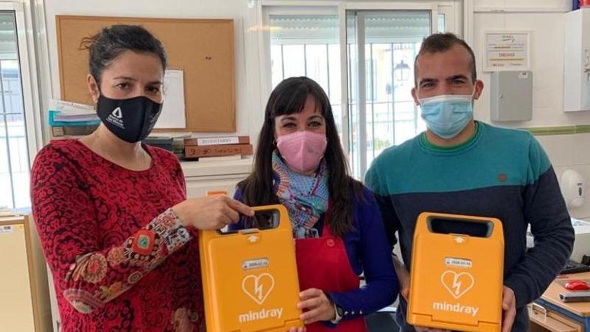 La alcaldesa de Monda, María Fernández, (a la izquierda), entrega uno de los desfibriladores en el colegio.