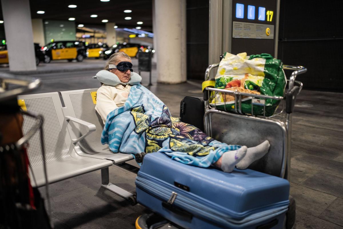 Una mujer sin hogar duerme en el exterior de la terminal 1 del aeropuerto de Barcelona.