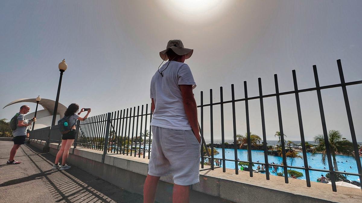 Un hombre contempla el Parque Marítimo de Santa Cruz resguardándose del sol con un sombrero.