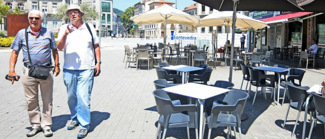 Dos turistas pasean delante de una terraza vacía. |   // GUSTAVO SANTOS