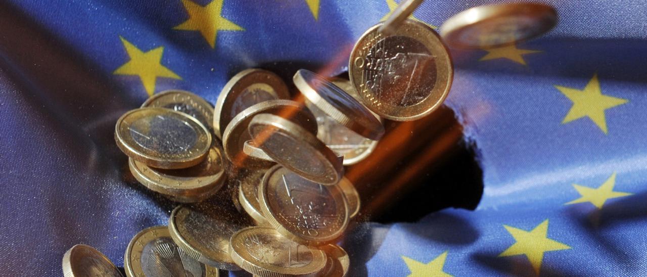 Archivo - FILED - 04 July 2011, Baden-Wuerttemberg, Karlsruhe: One euro coins will fall onto an EU flag. The European Union&#039;s gross domestic product shrank 3.5 per cent in the first three months of the year, according to a first estimate from Eurostat, wh