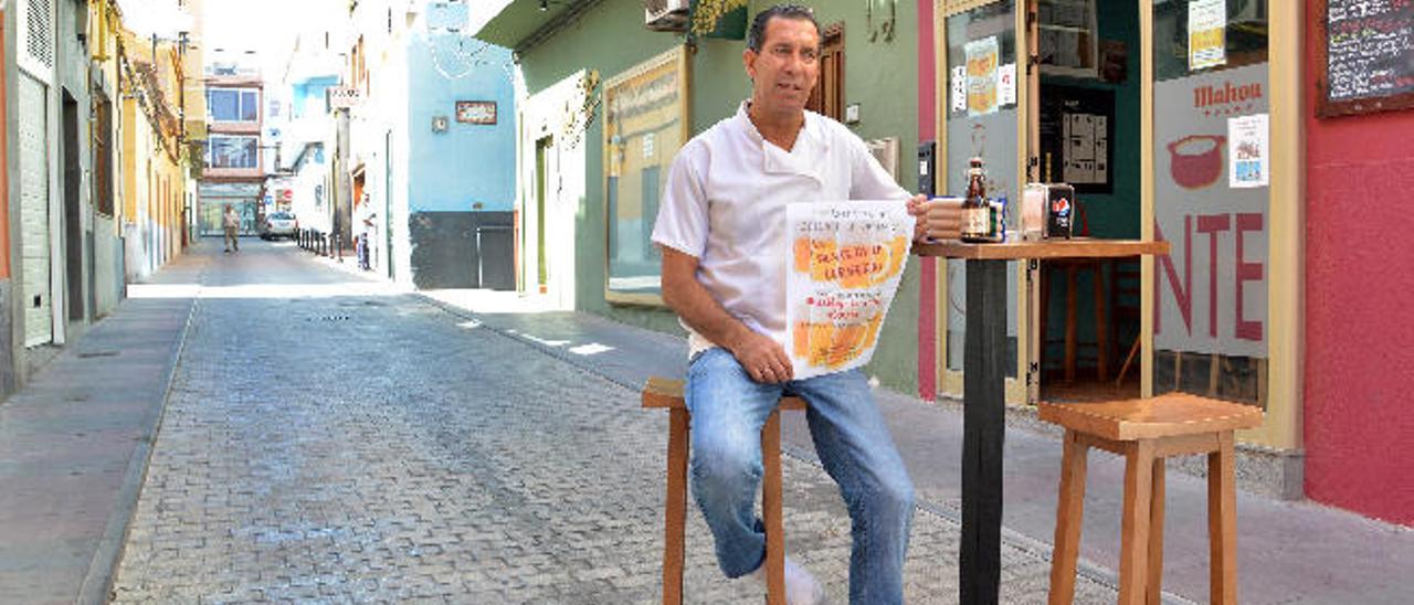 Enrique Ojeda, con el cartel anunciador de la fiesta, en una mesa de su local en la calle Betancor Fabelo.