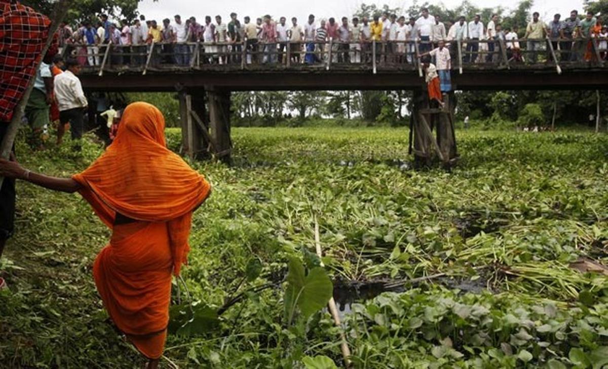 Un grup de vilatans observen una operació de rescat d’un bus accidentat a Charabari, a prop de Hajo, uns 40 quilòmetres a l’oest de Gauhati (Índia).