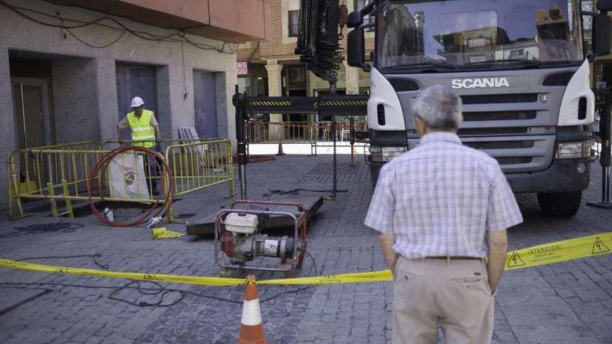 Un vecino observa los trabajos de operarios de Iberdrola en el CT de la plaza de San Nicolás.