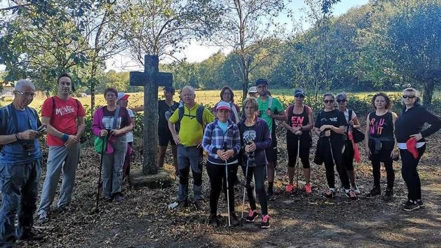 Un grupo de participantes en la caminata posa junto a una cruz carlista.