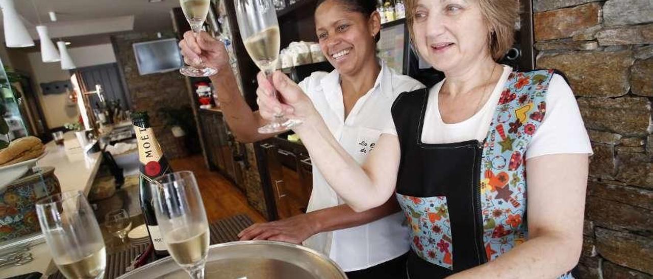 Yubelis Peña y Telvi García Castro, ayer, en el restaurante de Pravia, brindando con el décimo premiado en el sorteo de la Lotería Nacional.