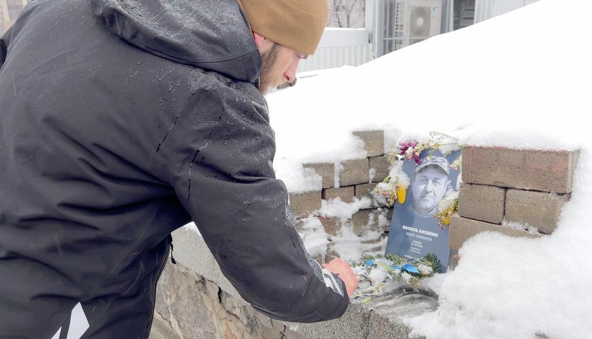 Yurii Aksenyn, hijo de un asesinado en Maidán en 2014, coloca una fotografía de su padre en la plaza de Kiev.