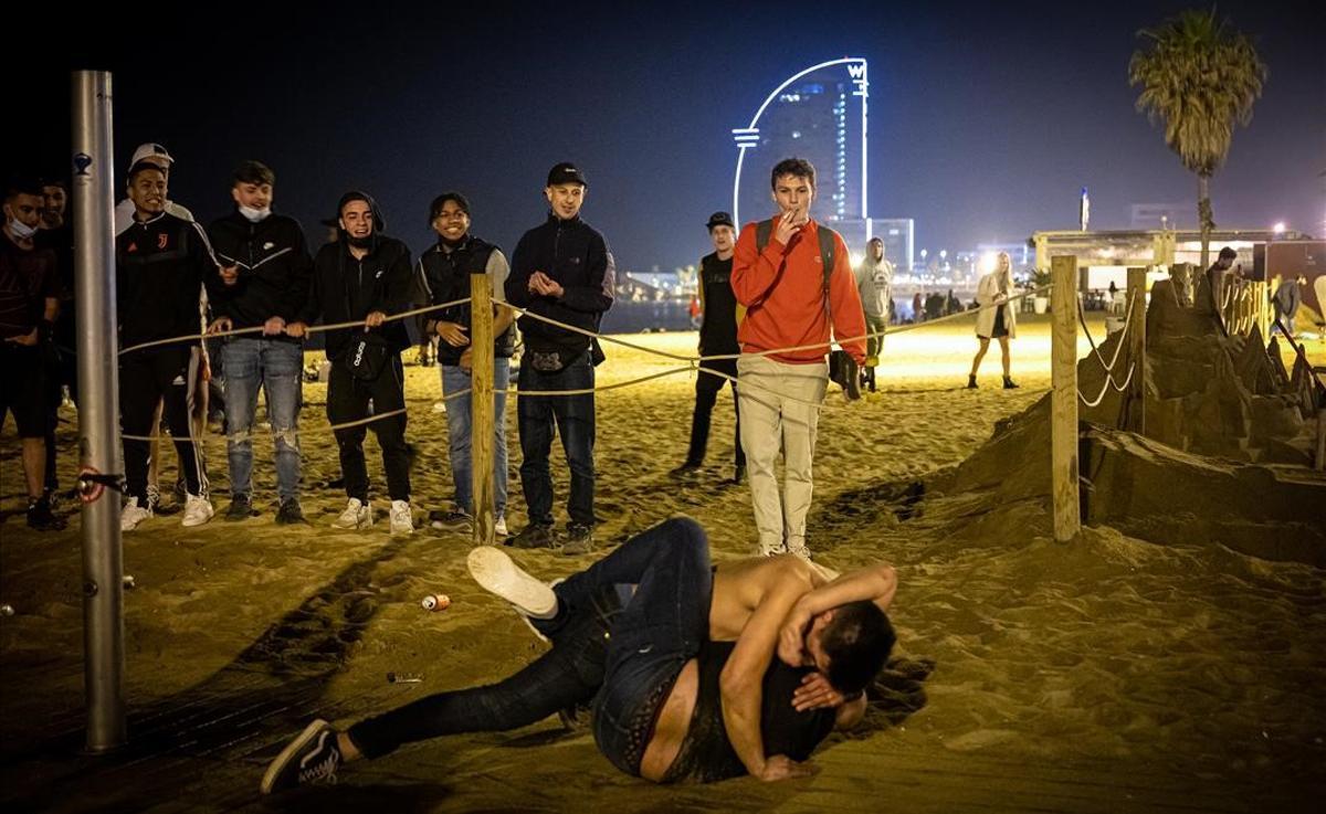 Dos jóvenes se pelean en la playa de la Barceloneta.