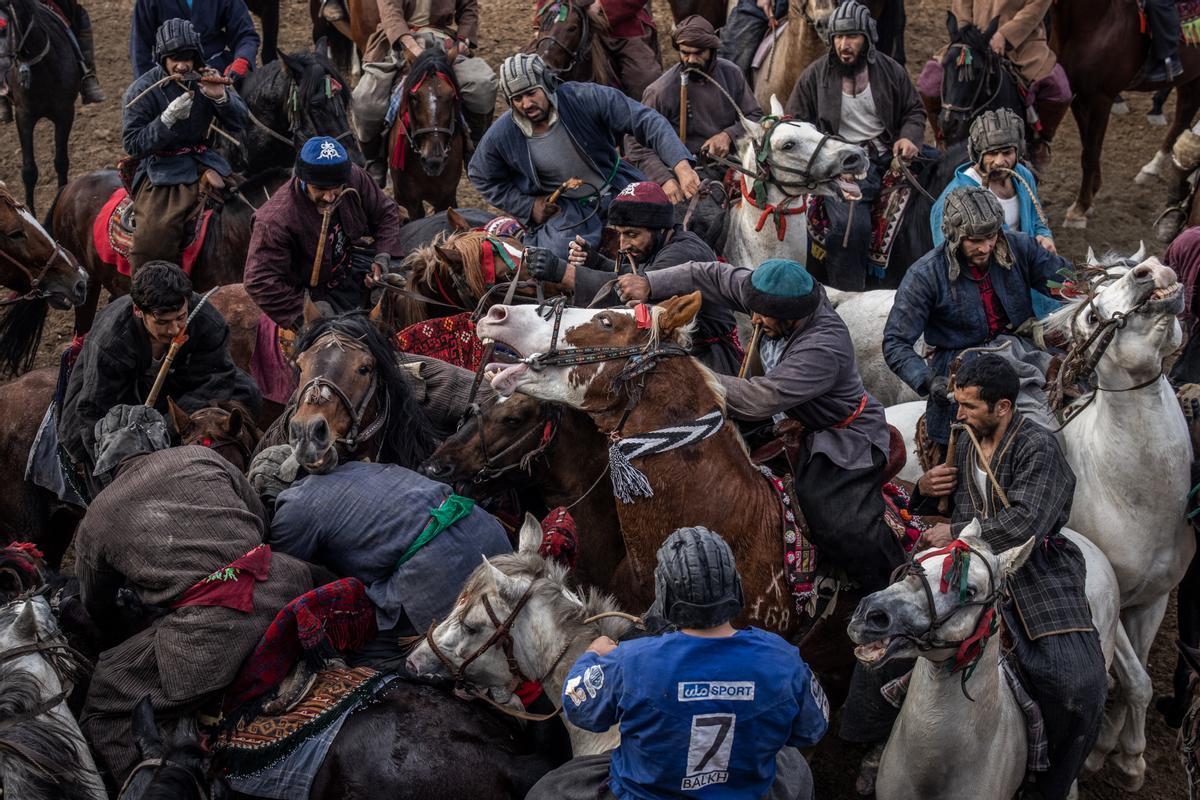 Jinetes afganos compiten en un deporte tradicional de Asia Central, en el que los jugadores montados a caballo intentan colocar una bolsa que se asemeja a un cadáver de cabra en una portería