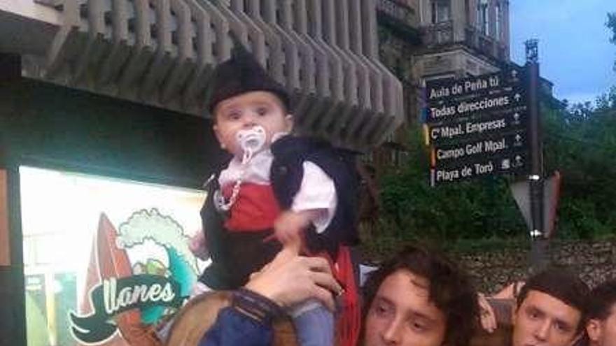 El pequeño David Martín, de cinco meses, subido a la hoguera en su recorrido por las calles de Llanes.