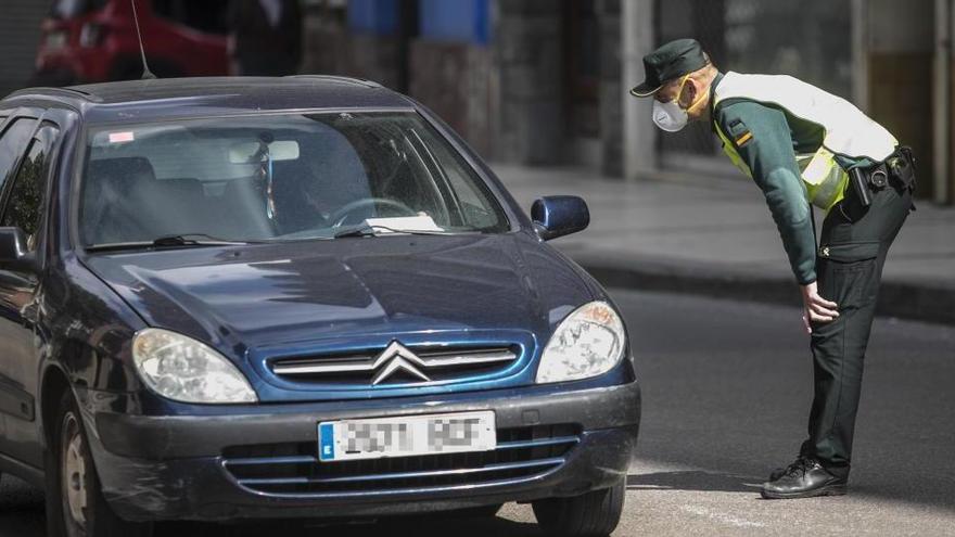 Un agente de la Guardia Civil, junto a un vehículo parado.