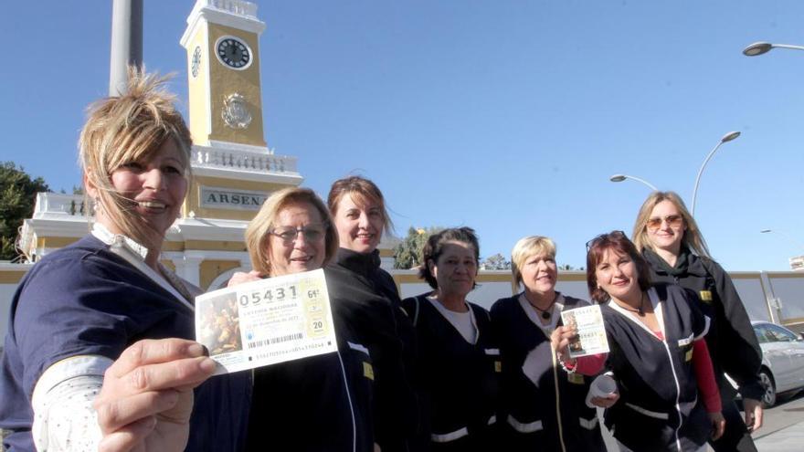 Las trabajadoras del servicio de limpieza del Arsenal de Cartagena muestran los décimos premiados frente al complejo militar.