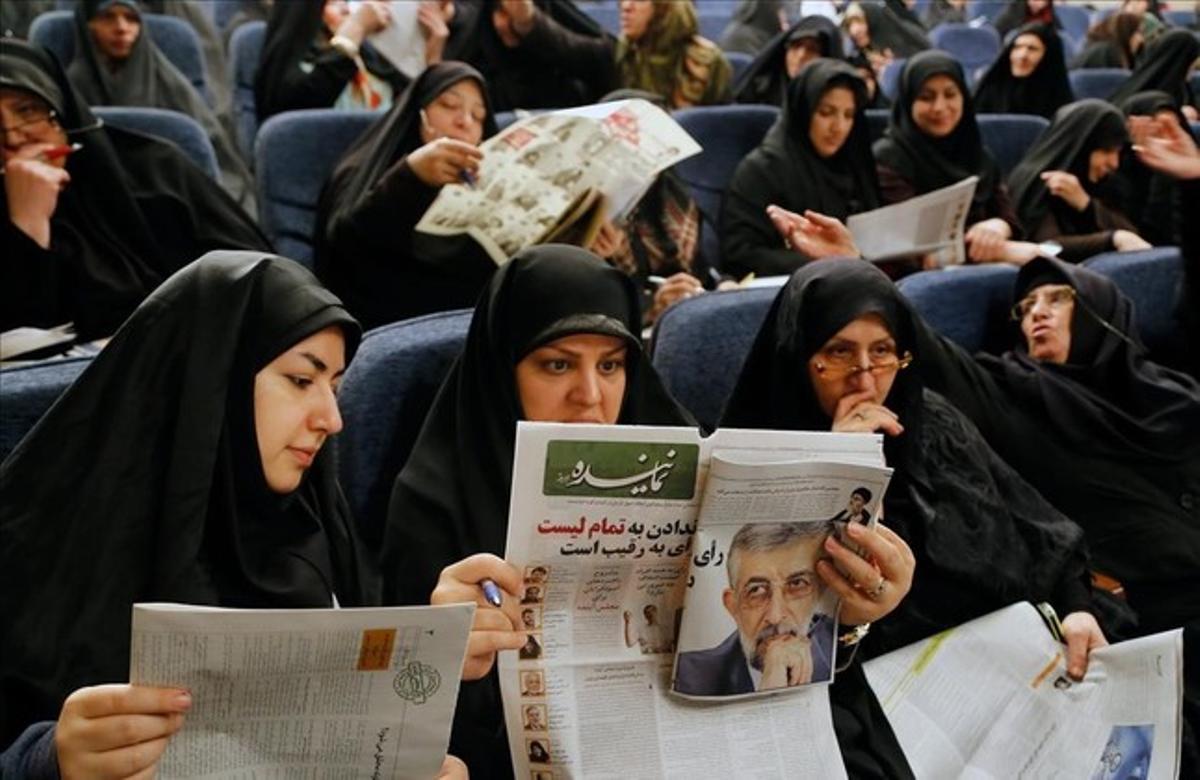 Unas mujeres leen en un acto electoral propaganda de uno de los candidados conservadores al Parlamento.