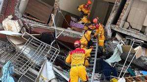 Un grup de bombers treballa en un edifici afectat, a Hualien. | BOMBERS DE TAIWAN / REUTERS