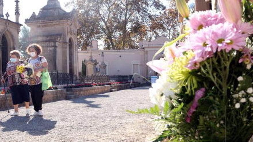 Un ram de flors i de dues dones caminant pel cementiri de Tarragona en la festivitat de Tots Sants