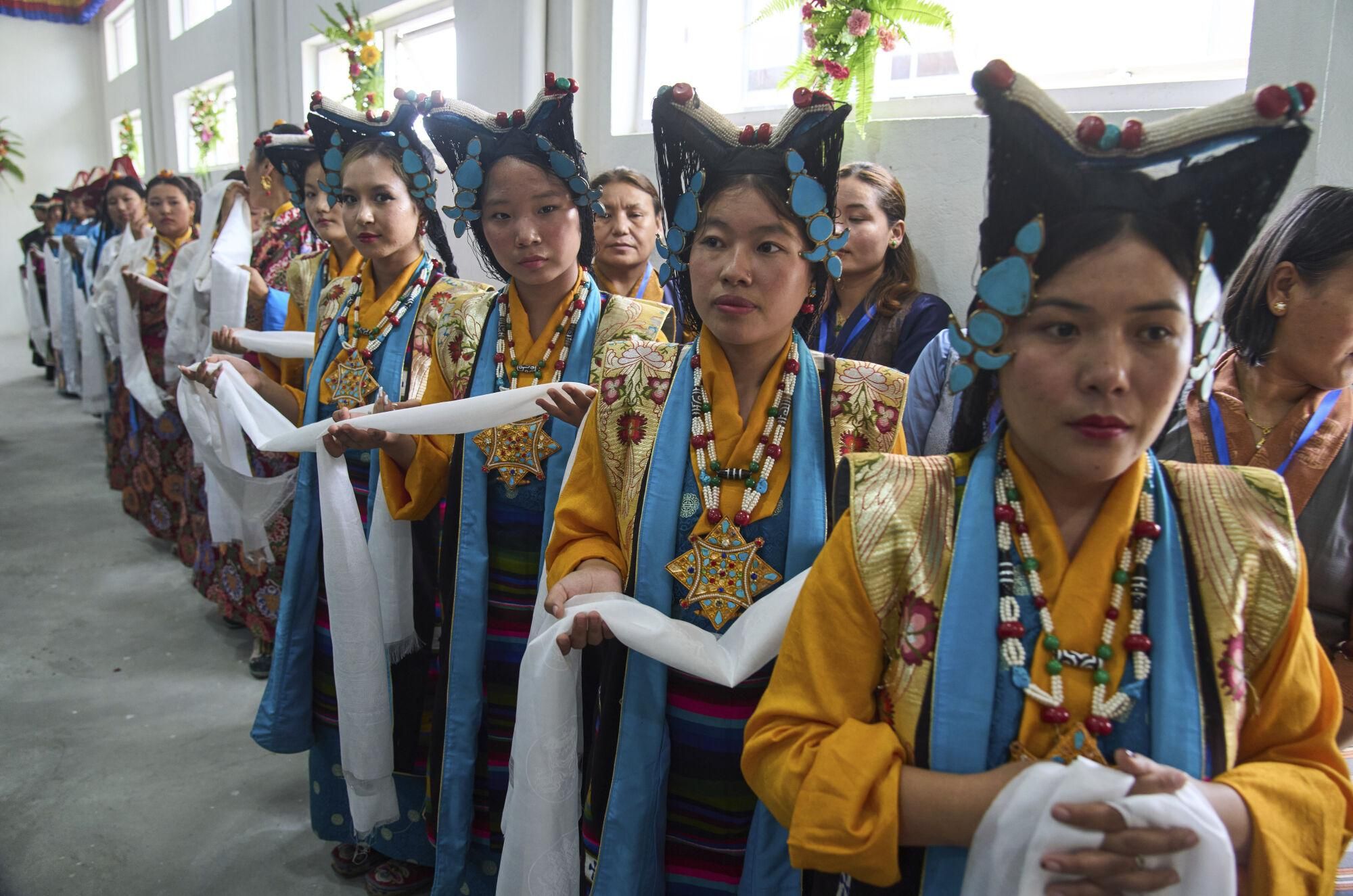 Exiled Tibetan women in traditional attire carry ceremonial scarf as part of the rituals during the 90th birthday celebration of spiritual leader the Dalai Lama at the Tibetan Camp in Kathmandu, Nepal, Sunday, July 6, 2025. (AP Photo/Niranjan Shrestha)