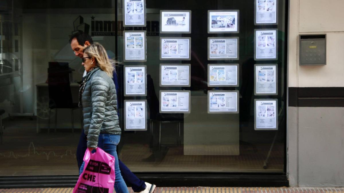 Una pareja pasea por delante de una inmobiliaria de Cullera, en una imagen de archivo.